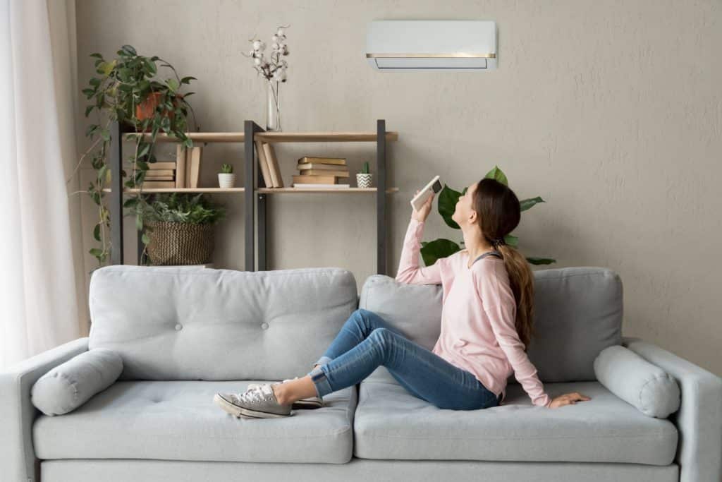 woman sits on sofa in front of heater