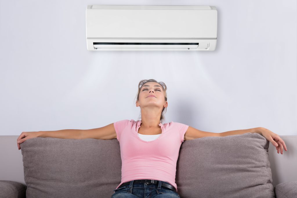 young woman sitting on sofa underneath air conditioner